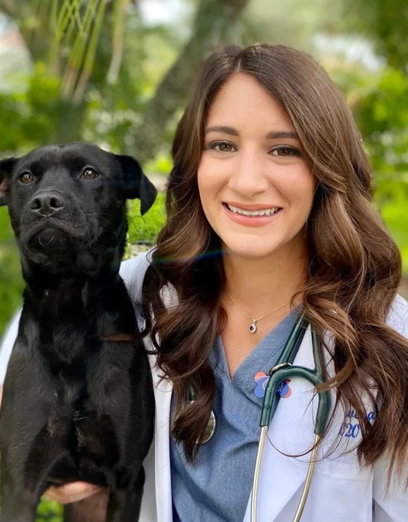 Dr. Katherine Rivera's staff photo where she is holding her black dog next to her.